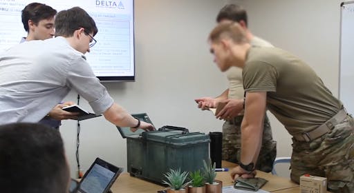 Robert Futch examining a unit alongside men in camouflage